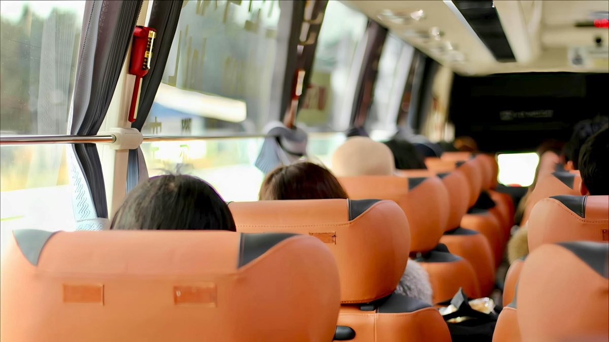 Passengers seated comfortably inside a tour bus, one option among Hiace, Elf, and bus classes for group travel