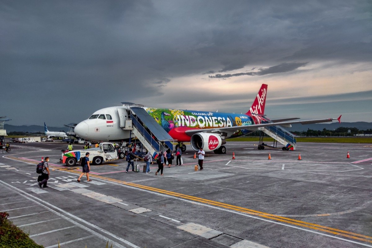 Airport runway with commercial aircraft, representing Husein Sastranegara's return to scheduled service