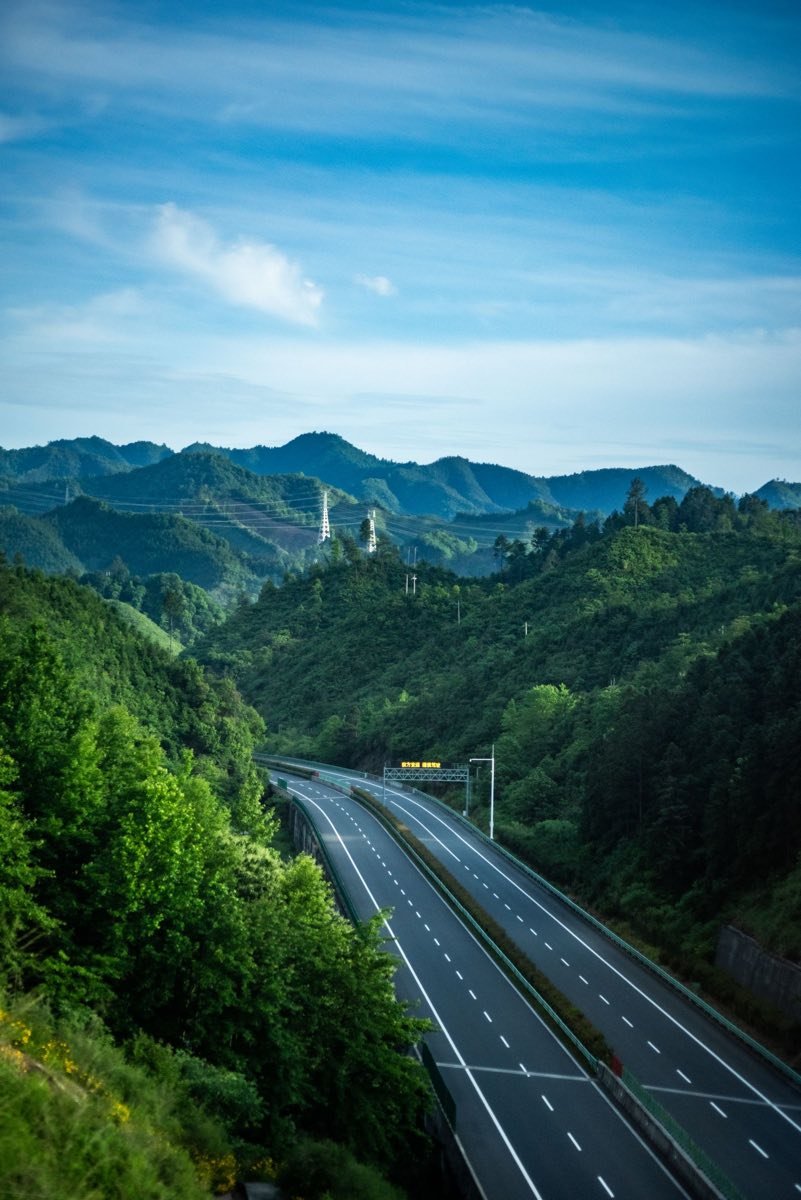 A highway winding through green hills, similar to the Cipularang toll road between Jakarta and Bandung